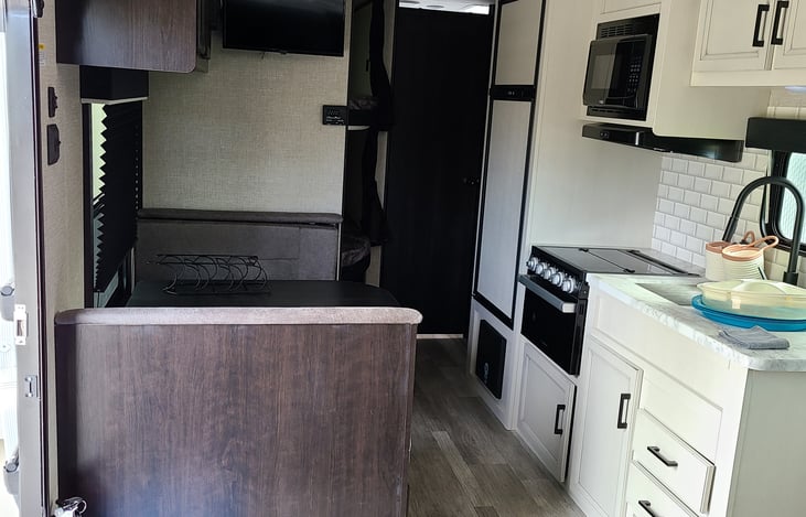 The kitchen is fully equipped with a microwave, stove, and refrigerator, making it easy to cook meals whether you're at a campsite or off-grid. There’s plenty of space to prep food and store your esse
