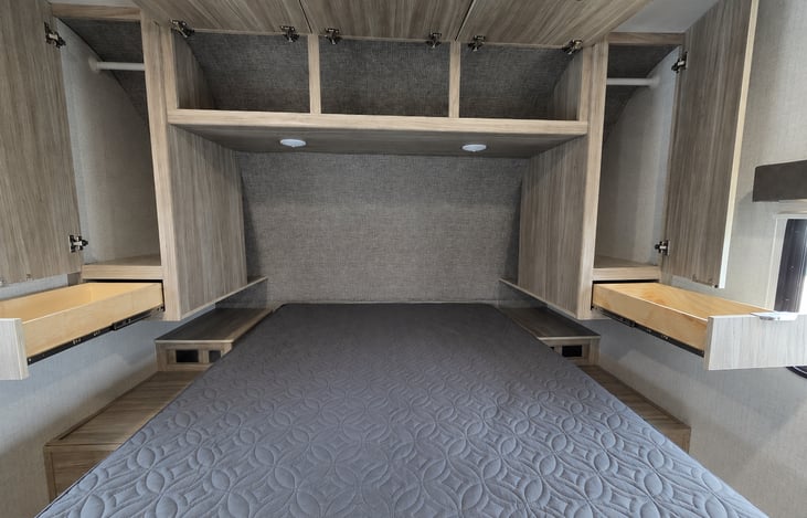 Tons of storage in the primary bedroom. Wardrobes and drawers on both sides, as well as overhead cabinet space and storage beneath the queen sized bed