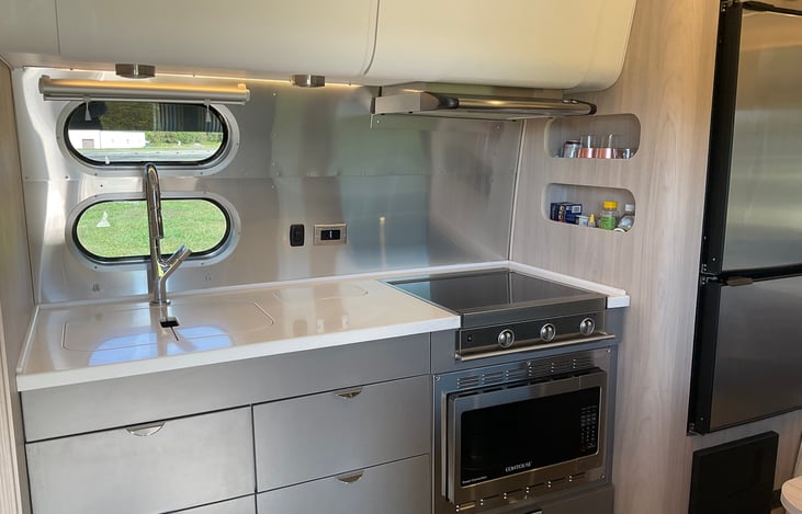 Gourmet kitchen with propane cooktop, convection microwave, sink, exhaust hood and plenty of storage.