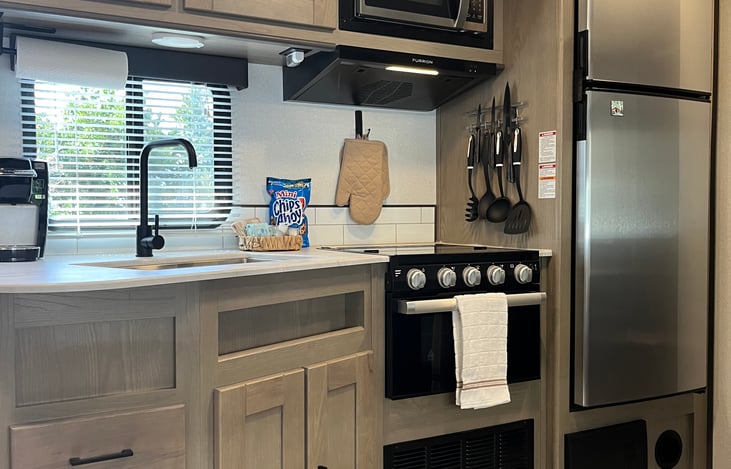 Refrigerator, large sink, microwave, oven, and stove.