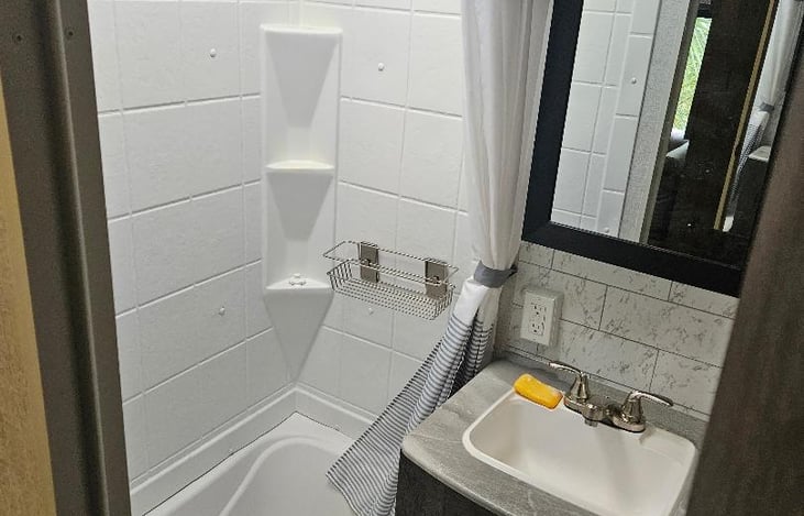 Bathroom with backdoor access and tub/shower combination.