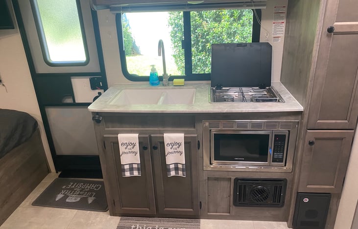 Indoor kitchen with large sink, 3 burner stove and microwave.