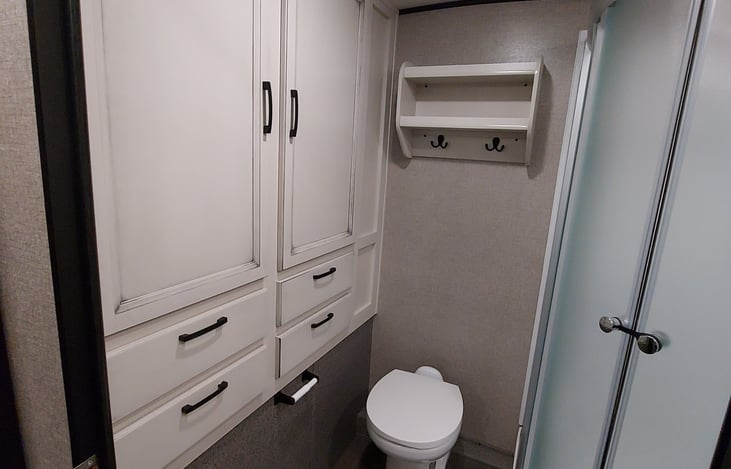 Large bathroom with plenty of drawers and cabinet storage with pole for hanging clothes.