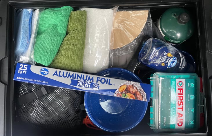 The camping box has all the basic necessities.  Cookware, silverware, cups, bowls, plates, stove, propane, scrubber, trash bags, microfiber hand towels, napkins coffee filters, strainer and more.