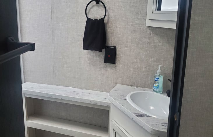 4 towels and 2 wash clothes stored above sink.  Under sink is extra RV toliet paper and blow dryer.