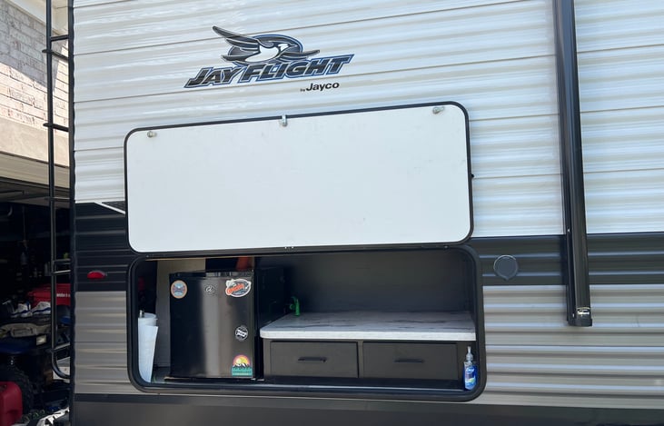 Outdoor kitchen area equipped with grilling utensils and paper towels.