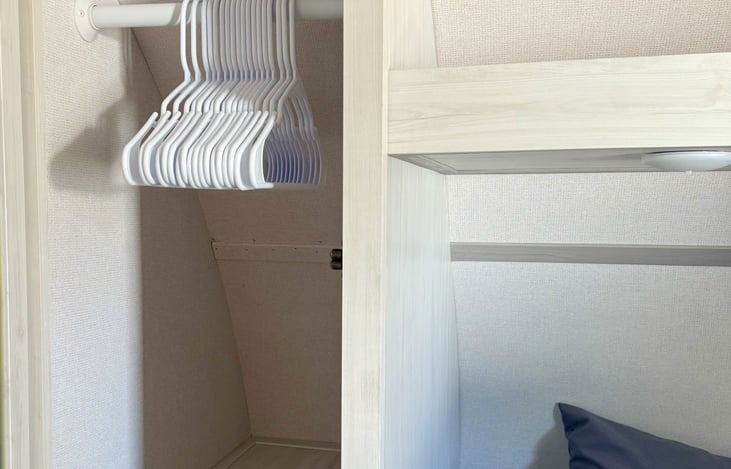 Master bedroom includes a mini closet on each side of queen bed stocked with hangers.