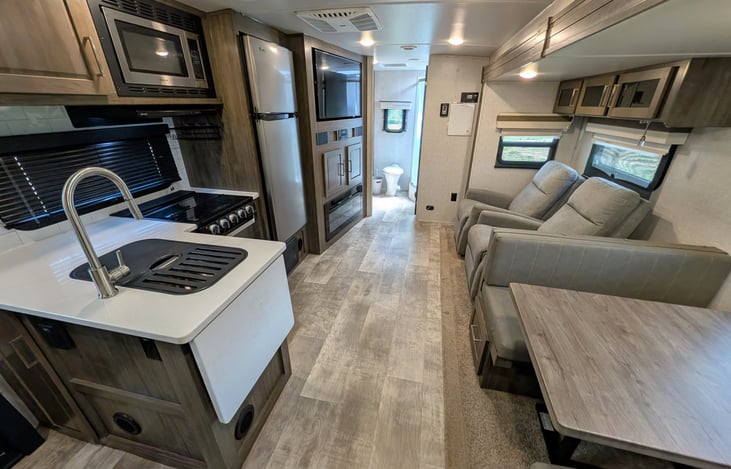 Spacious open-concept living area w/ dual recliners, TV & fireplace. Full kitchen features a residential fridge, 3-burner stove, oven, microwave, deep sink & booth dinette! Natural light throughout.