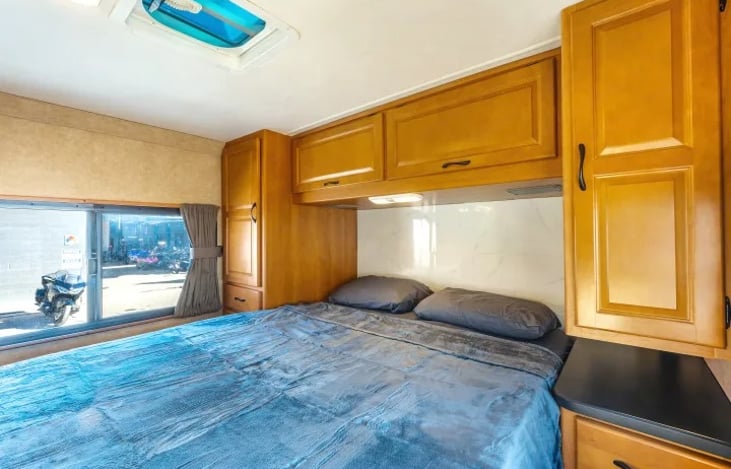 Spacious rear bedroom suite with wardrobe storage and soft lighting — unwind in your Class C motorhome after exploring Zion, Red Rock Canyon, or Burning Man.