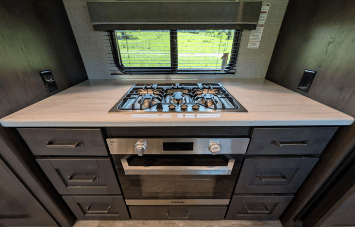 Gourmet galley & rear den retreat! Includes a 12 cu ft fridge, pantry, stove/oven, dual sofas, theater seats, 50" TV, electric fireplace, and 3 slides for spacious high-end living.