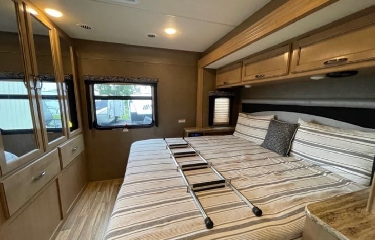 rear bedroom with king size bed, tv and lots of storage. ladder for over cab bunk
