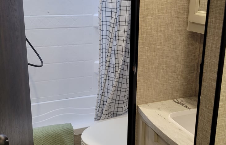 Bath/shower combo and toilet with a door for privacy.