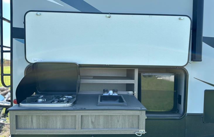 Outdoor kitchen with small refrigerator and stove.