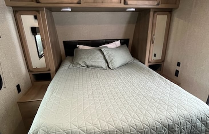 Queen bed surrounded by cabinets for storing clothes and personal items. Under bed storage makes a great place to store dirty laundry while camping.