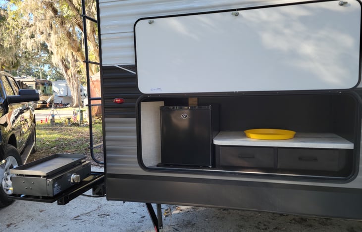 Outdoor kitchen equipped with mini fridge and propane griddle.