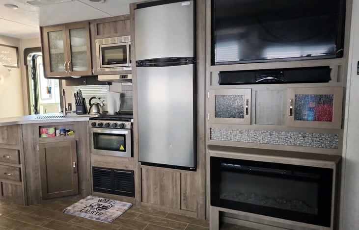 Fully stocked kitchen, microwave, entertainment center, and electric fireplace.