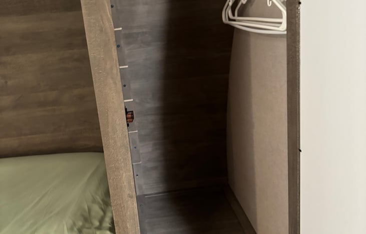 Closets on both sides of the bed with bar for hanging clothes.