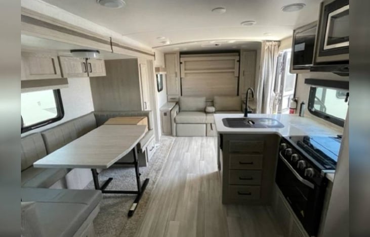 Interior Layout with Fold up Murphy Bed, 6-Person Dinette, 3 Burner Stove, Dual Sink, Fold up Counter Space, Microwave.