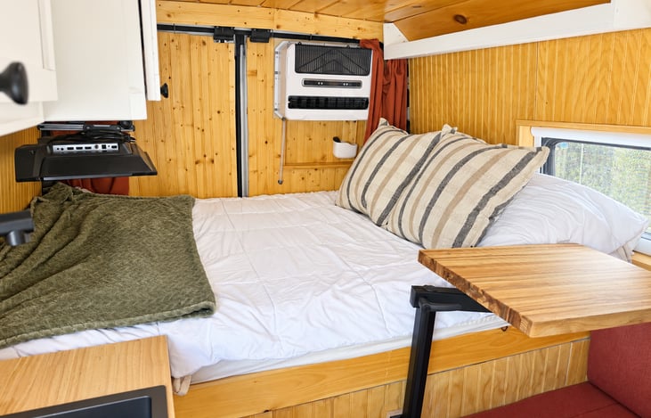 Cozy sleeping area with a comfortable full-size bed, warm wood interior, bedside storage, and easy access to the living space. Perfect for relaxing after a day of exploring.
