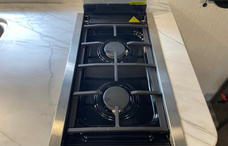 Double burner propane stove with overhead light and exhaust fan.