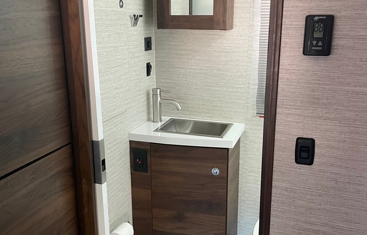 View through bathroom pocket door shows sink and medicine cabinet.