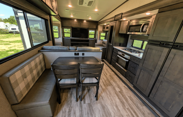 Gourmet galley & rear den retreat! Includes a 12 cu ft fridge, pantry, stove/oven, dual sofas, theater seats, 50" TV, electric fireplace, and 3 slides for spacious high-end living.