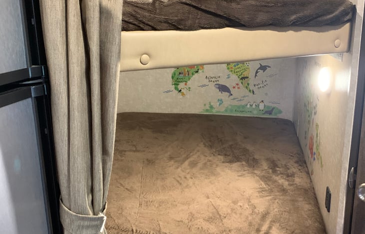 Bunk beds with USB port chargers on each bed, window with egress, light on each bed and the bottom bunk has some fun kids friendly stickers.