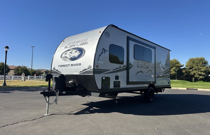 Front-quarter exterior view with hitch and campsite-ready setup.