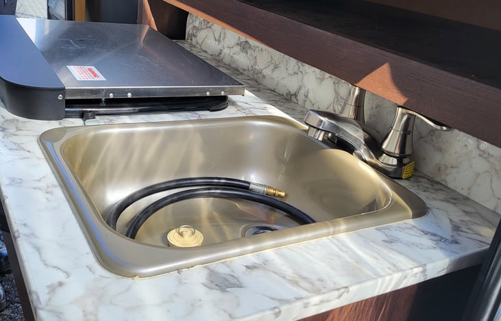 Out door kitchen with sink/faucet and stove top. Plus a refrigerator.
