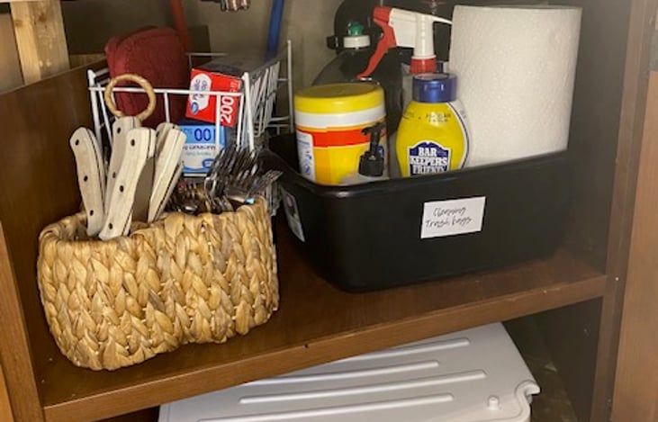 Under kitchen sink, flatware, steak knives, plastic wrap, aluminum foil, cleaning supplies, oven mitts, towels, dish rags and drying rack.