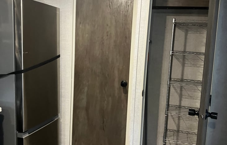 Frisge, bathroom door, large pantry with shelf