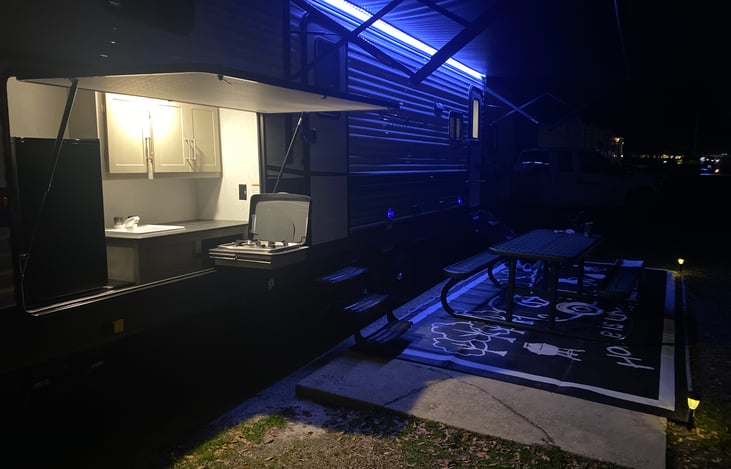 Outside kitchen with two burner stove top, refrigerator, and sink.