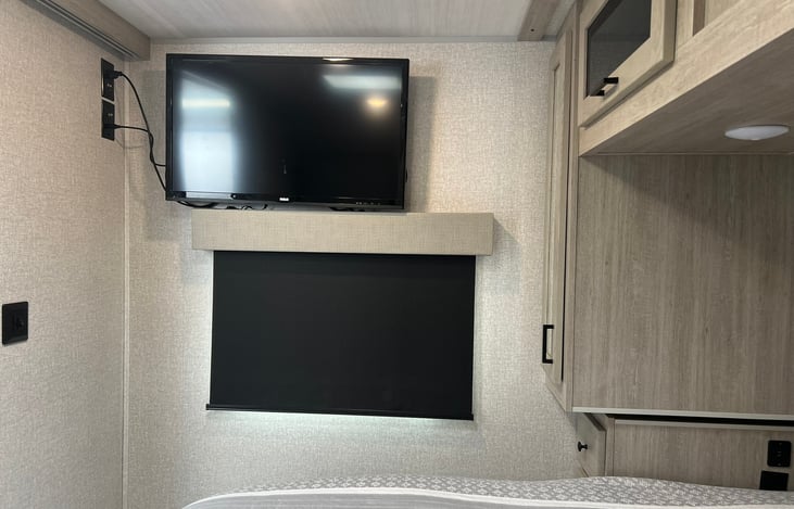 32 inch TV. A window under the TV with a darkening shade.