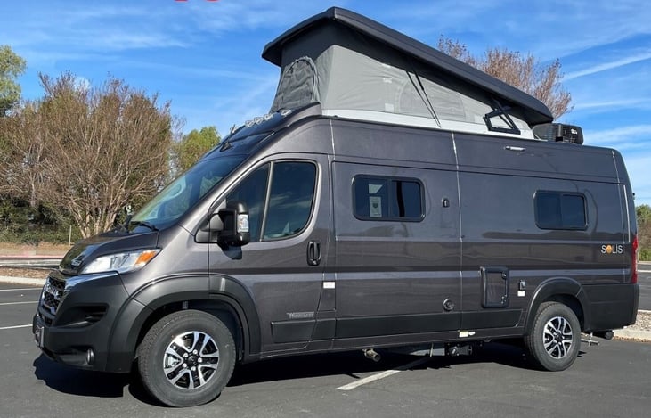 Capture the essence of adventure with a stunning exterior shot of our RV's driver's side featuring a pop-up top.