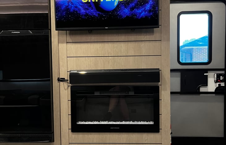 Flatscreen TV over fireplace with Bluetooth sound bar.