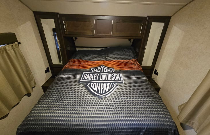 Camper queen size bed. With hanging closets on the side of the bed, and two large compartments above.There are electrical outlets and USB  outlets on each side.