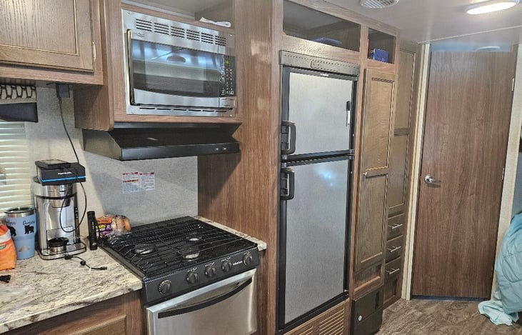 Kitchen area with stove, oven, microwave, Fridge, with a pantry to the right and then closest next to pantry