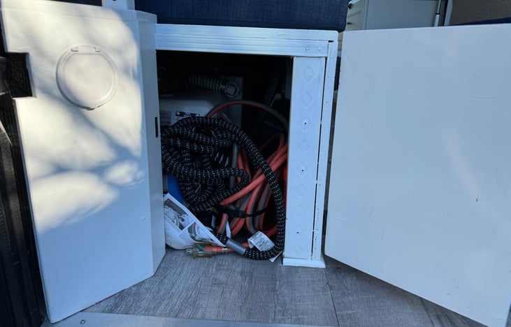 Under the left bench: Electrical cable to plug in to shore power and water hose to refill the water tank