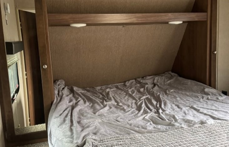 main bedroom with queen size bed with individual over head lights and each side of the bed has its own closet and overhead storage. Underbed storage as well.