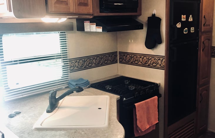 kitchen sink and gas stove with microwave and fridge, all basic kitchen items are provided including a coffee pot...