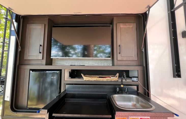 Outdoor kitchen: cooking utensils griddle, sink, fridge, smart tv