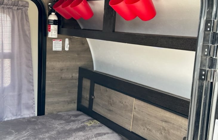Front of the bed with shelf, cups for the little things, fire extinguisher, and cabinet with sliding doors