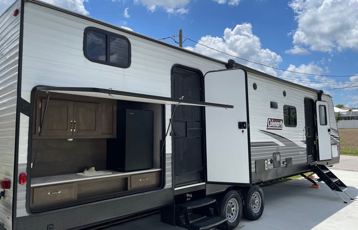 Rear kitchenette with refrigerator, sink, countertop, and cabinets for storage.