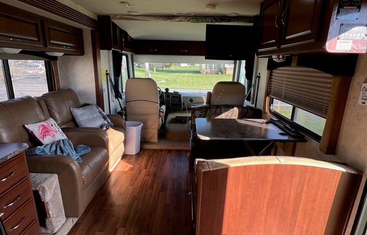 RV Main living area with two recliners, Dinette seating, flatscreen TV, and plenty of windows and storage.