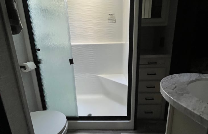 Master bath with full shower, toilet, sink, and towels.
