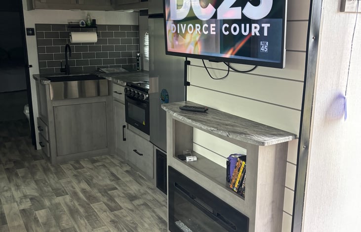 Kitchen with gas stove microwave and electric fireplace with pantry behind the tv and fireplace.