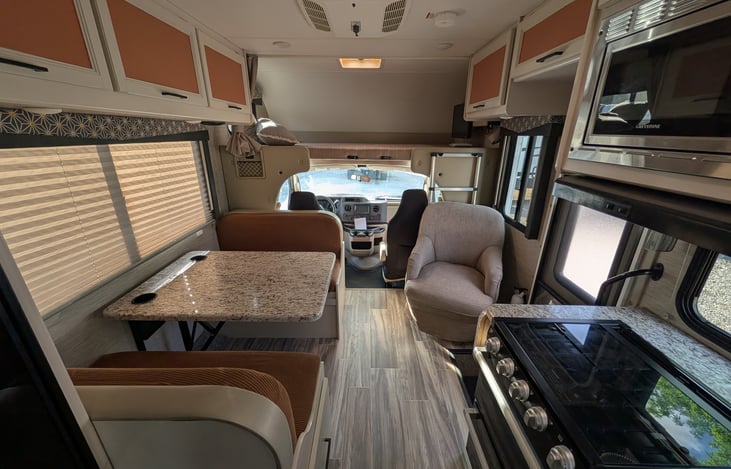 Bright, modern interior with a cute pop of color! Features a cozy rear queen bed, fully equipped kitchen, converting dinette, over-cab bunk, and an accent armchair. Clean, open, and ready for adventur