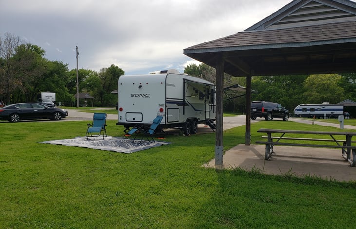 The travel trailer has a backup camera with a portable monitor provided at NO extra cost. The travel trailer also comes stocked with an outdoor rug and 2 lounge chairs