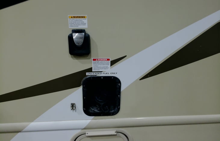 Power supply plug and unleaded gas tank on left side of RV.