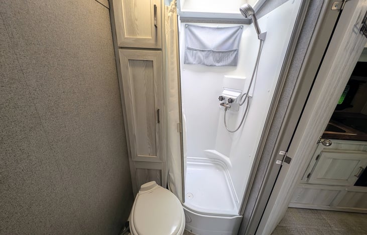 Convenient bathroom with ample storage, toilet and shower.